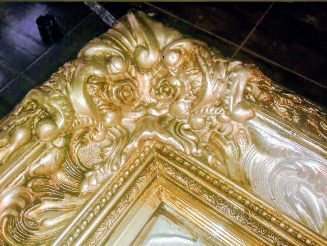 Närbild på renoverat ornament i förgylld antik ram